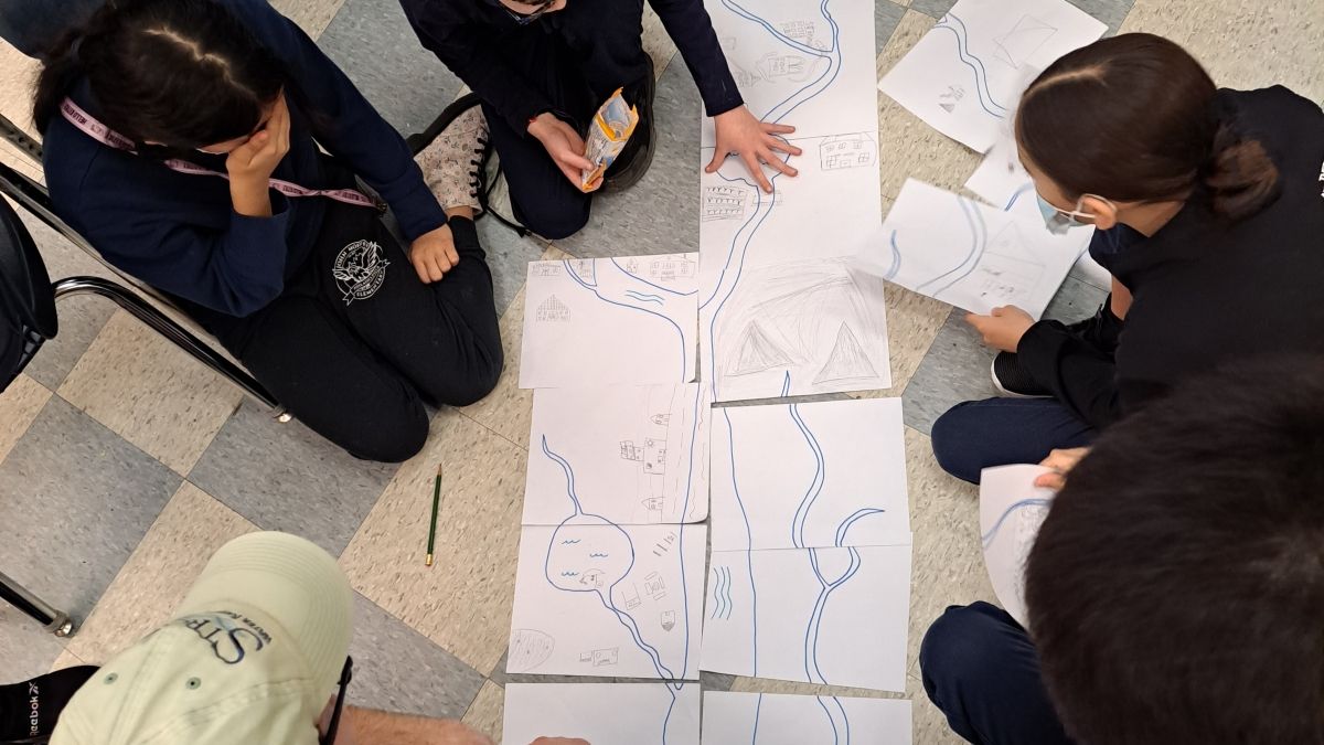 Group of students looking at an illustration of a waterway
