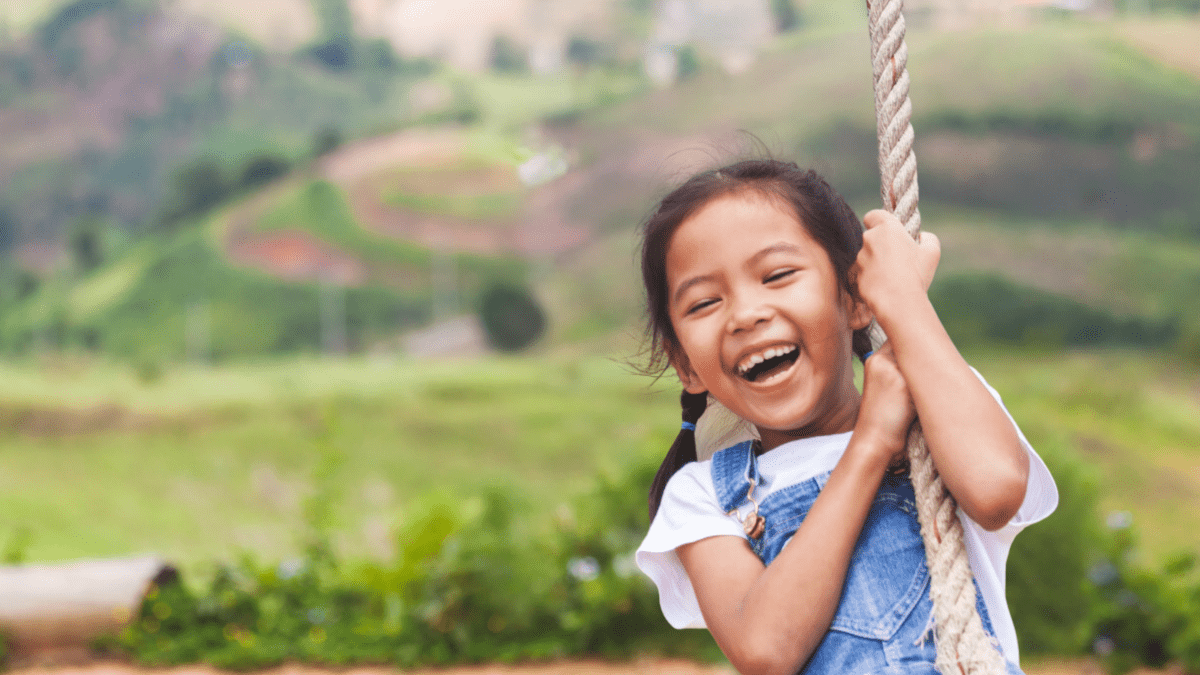 A young girl swings from a rope swing