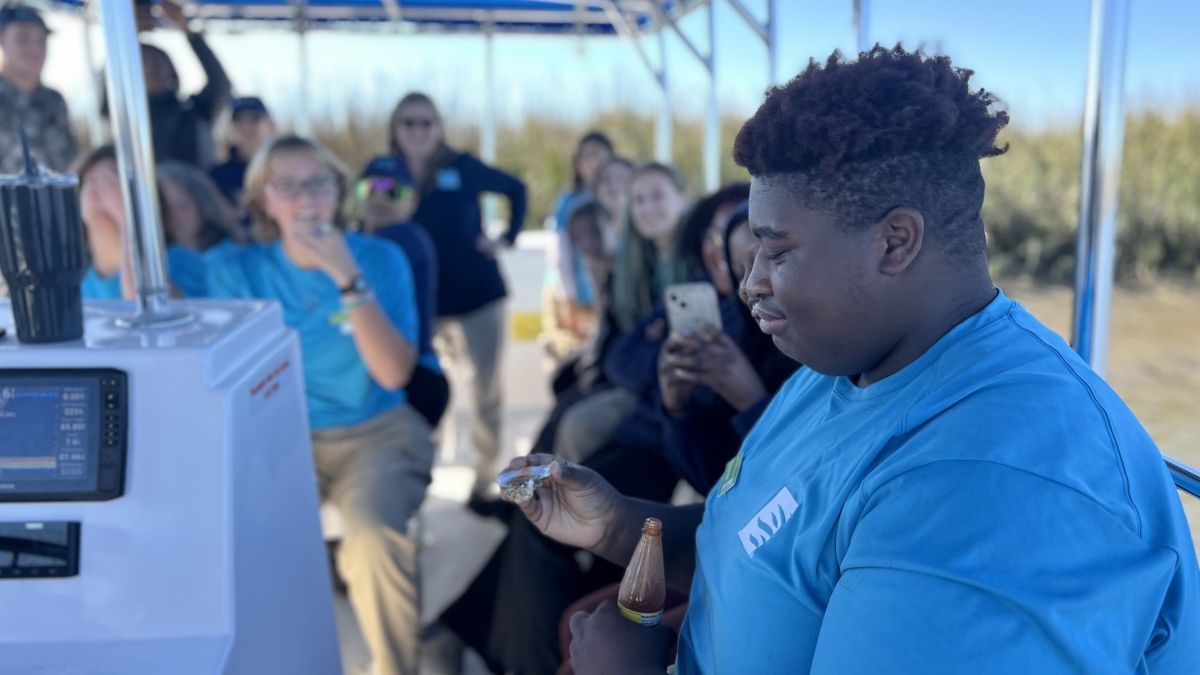 Student on a boat tries an oyster