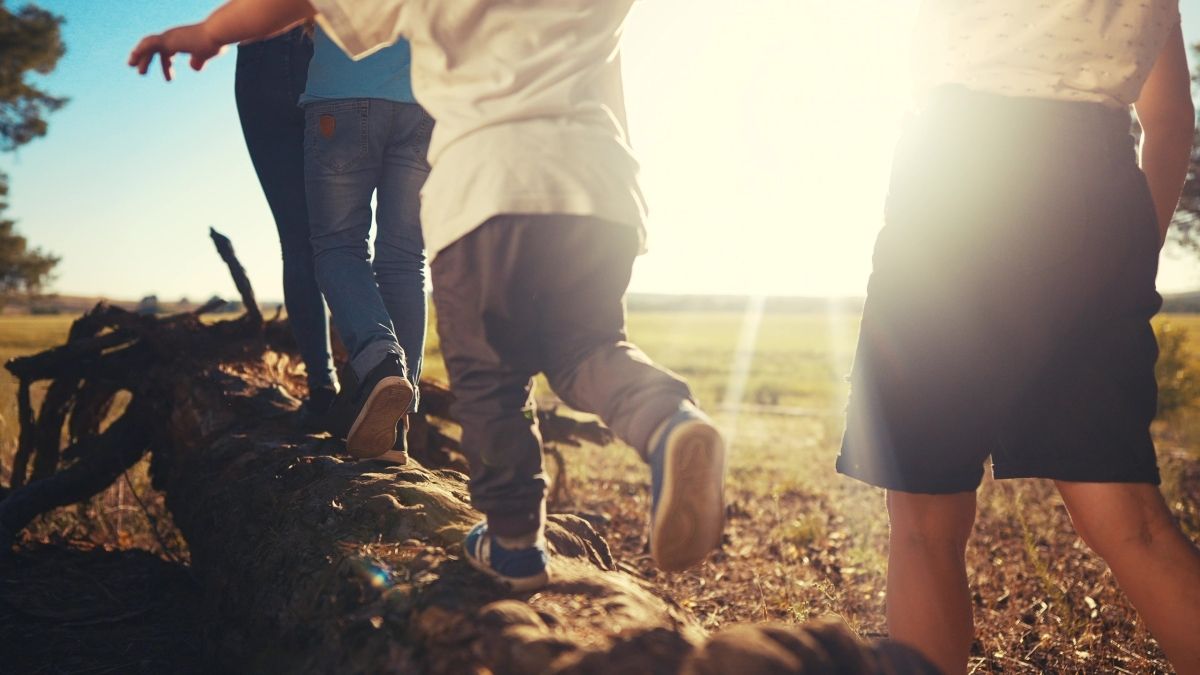 kids walking on log in sunlight