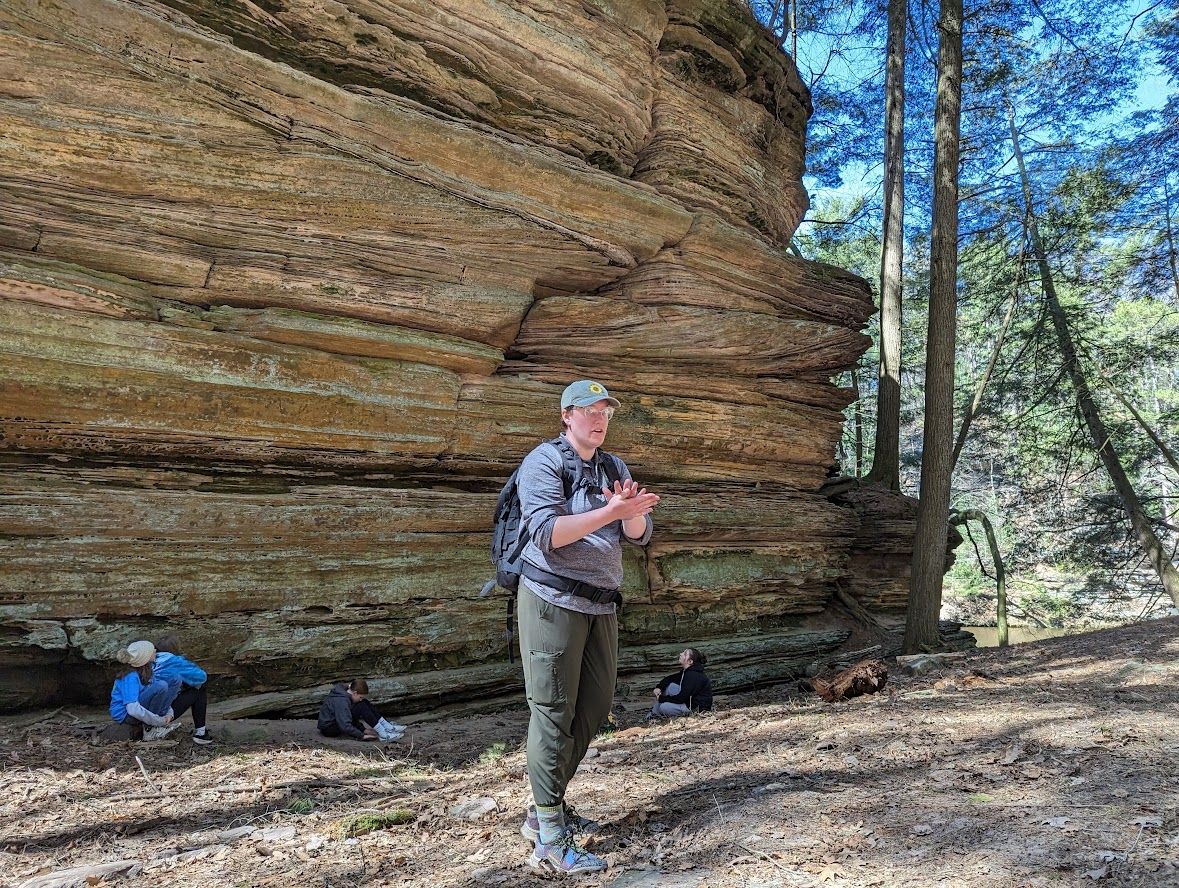 Rachael discusses sedimentary rock formation with students during a field trip.