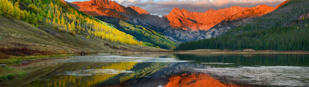 orange mountains at sunset reflecting on lake 