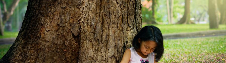 young girl journaling under tree