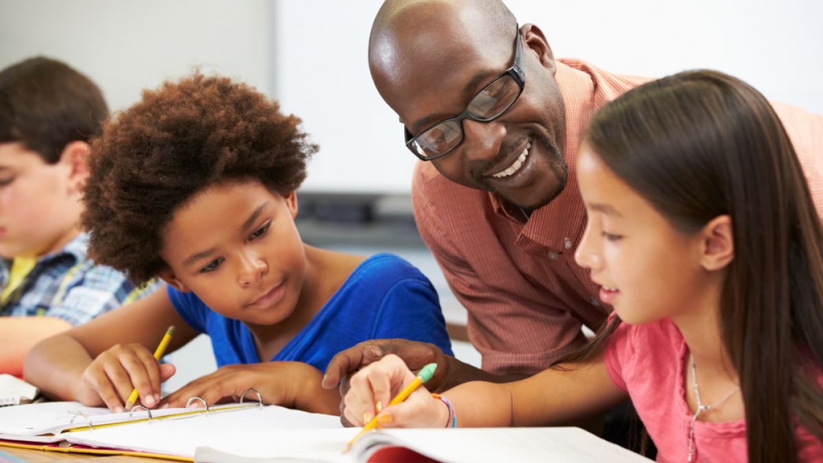 young students working with teacher in classroom