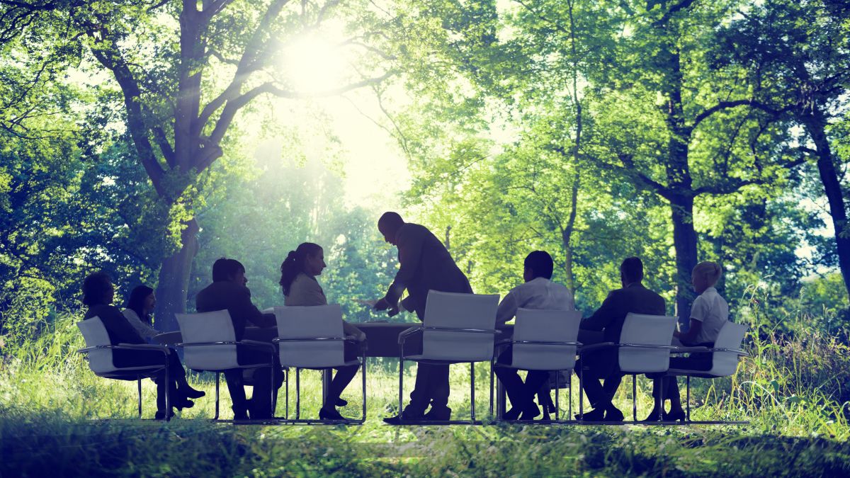 people sitting in a row of chairs outdoors in a park setting