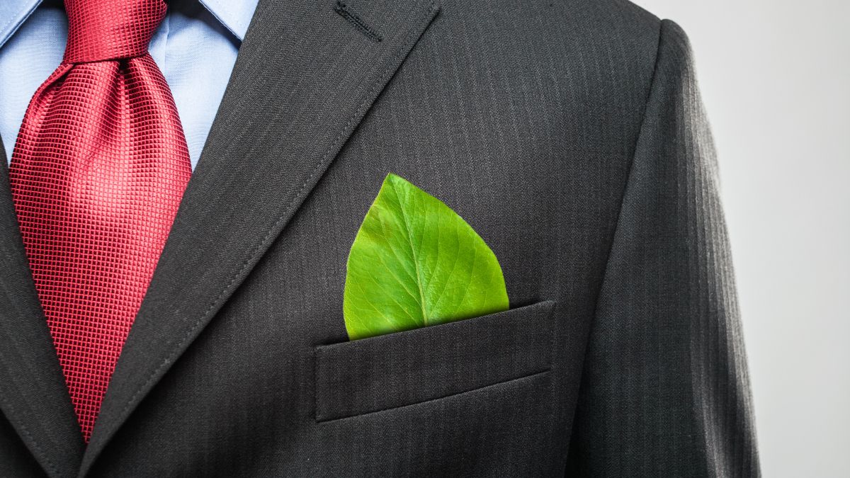 Person in brown suit with red tie and green leaf in top pocket