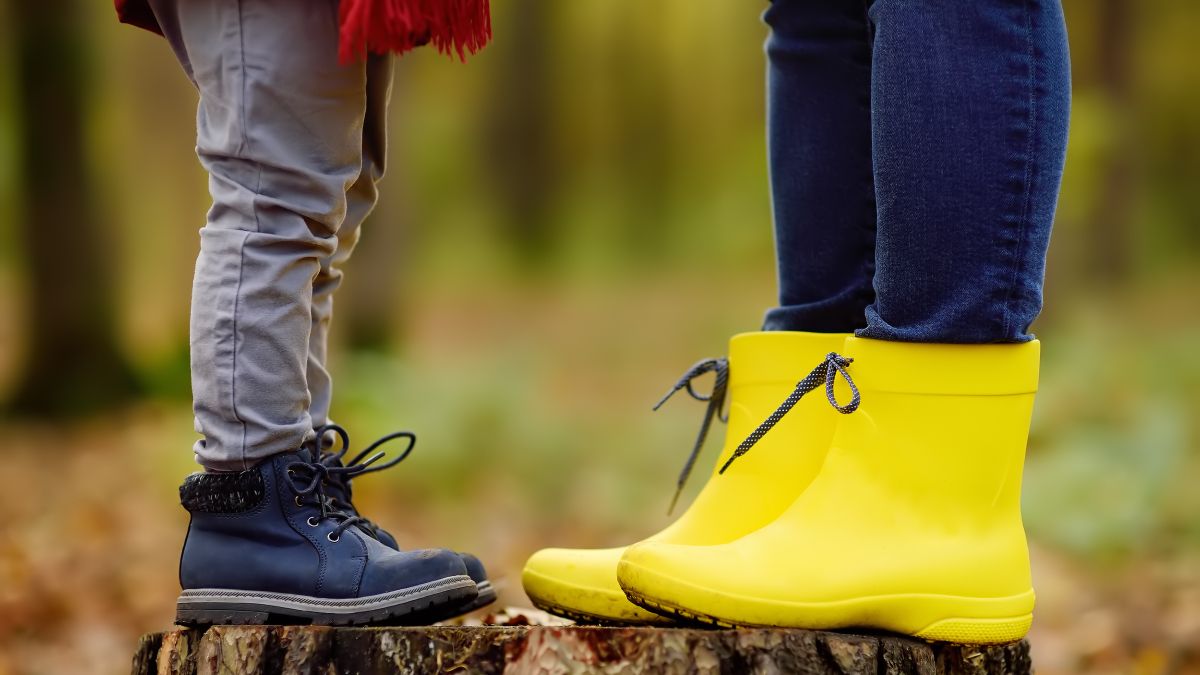child and adult in boots standing on tree stump