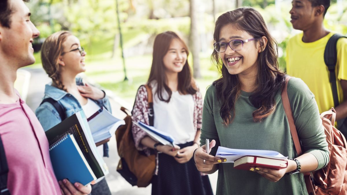 students gathering outdoors holding books