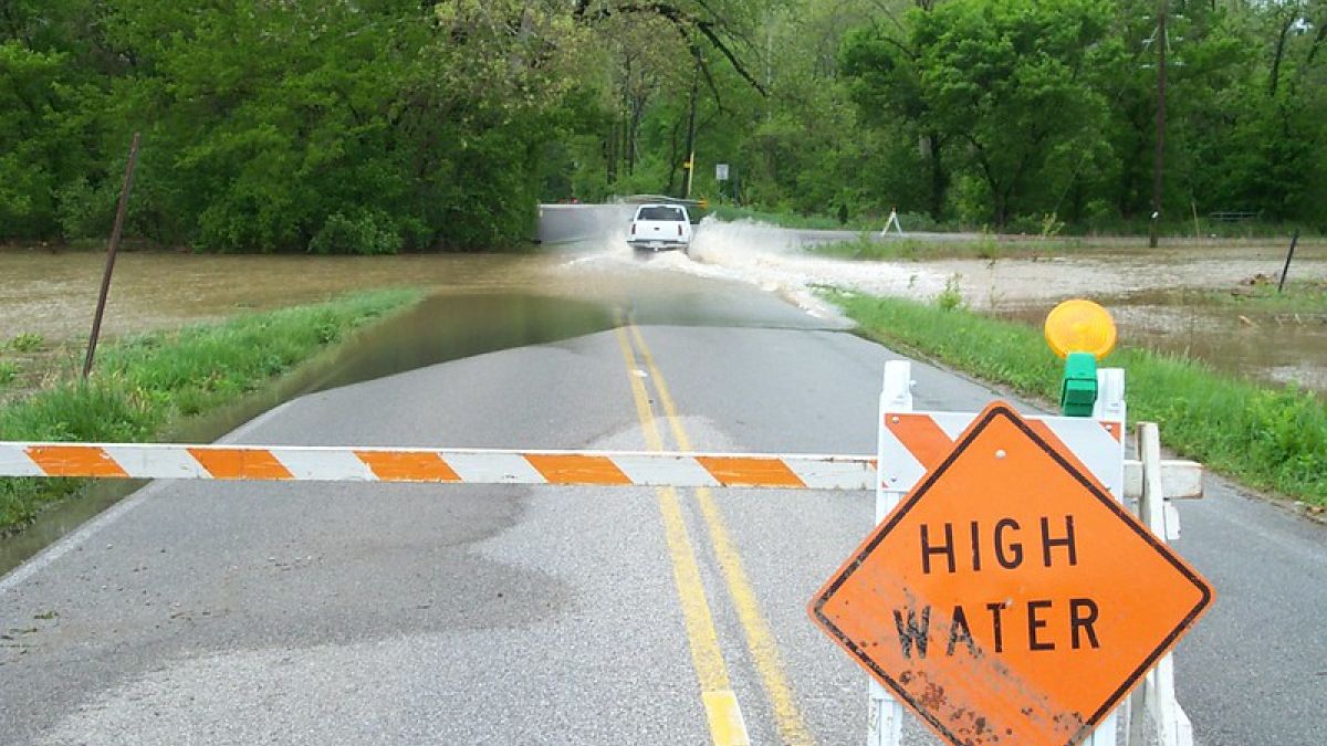 High water sign blocks part of a flooded roadway