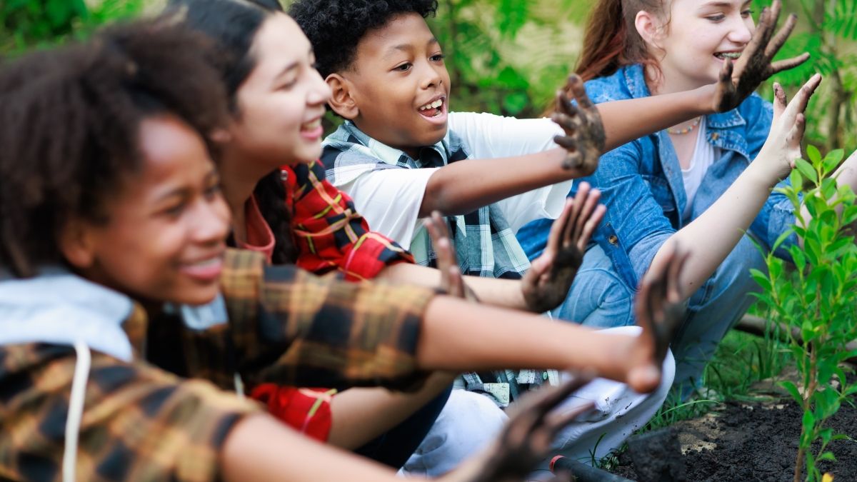 Four kids in a garden show their hands