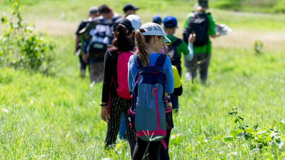 A group of people hike in a green field.