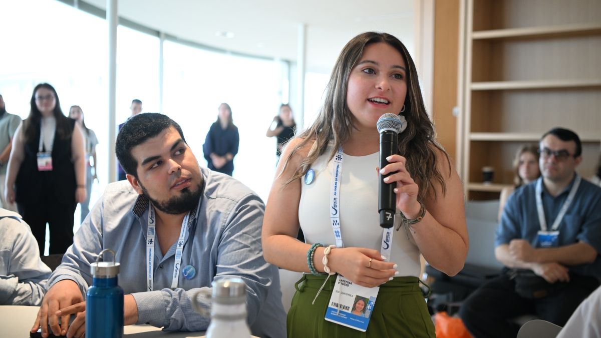 Young woman speaking in a microphone around a group of young professionals