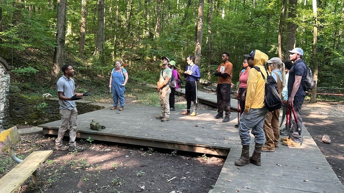 Naturalist speaking to a group of adults in a forest