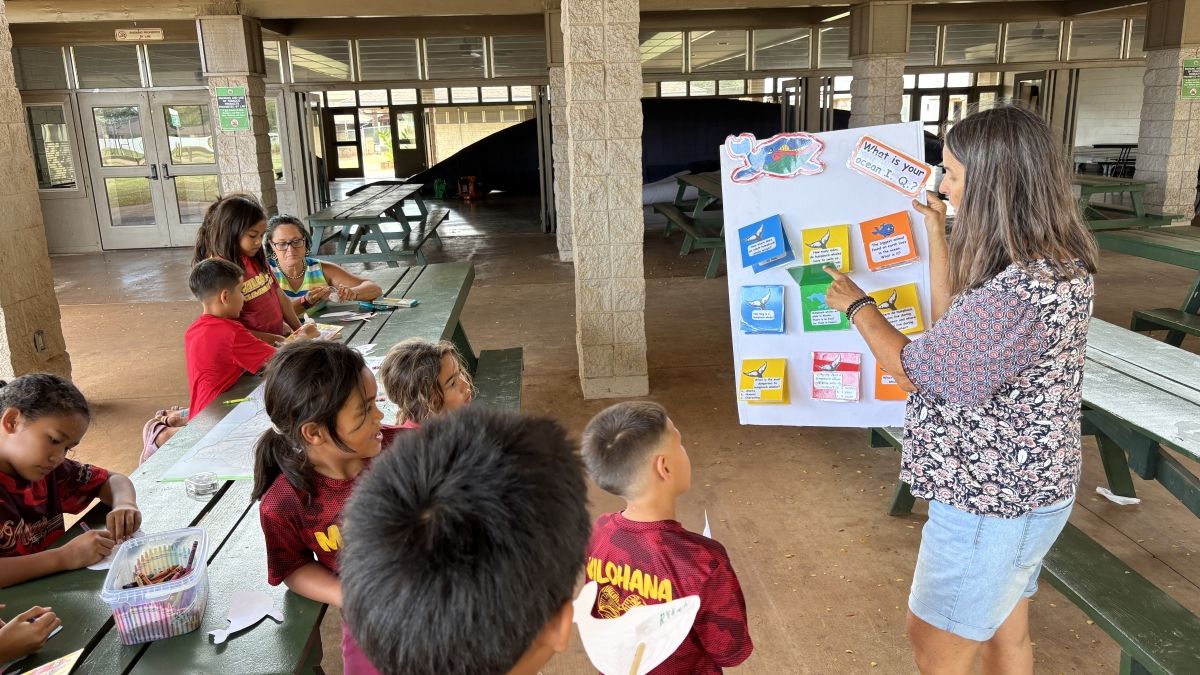 Students play the whale trivia game with Diana Warren, Learning Endeavors, while they wait to go inside the giant whale