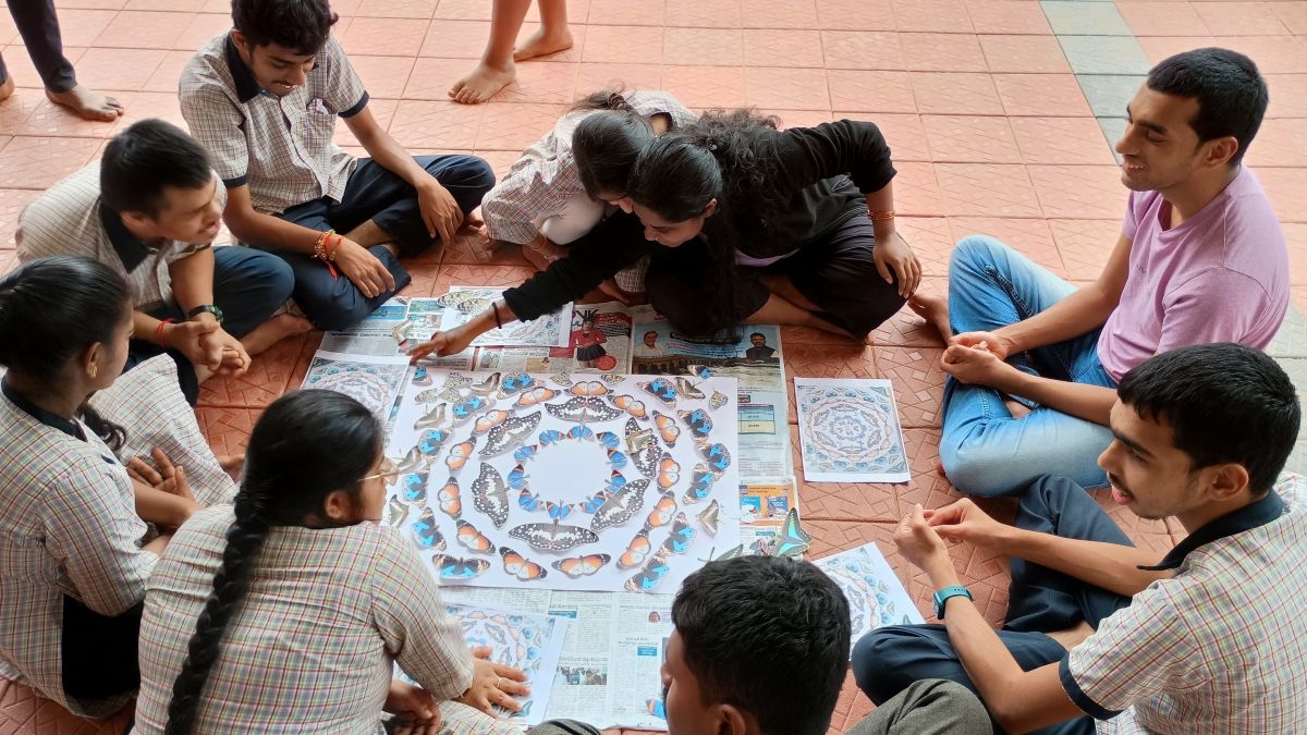 Children sitting cross-legged on the floor looking at a butterfly pattern