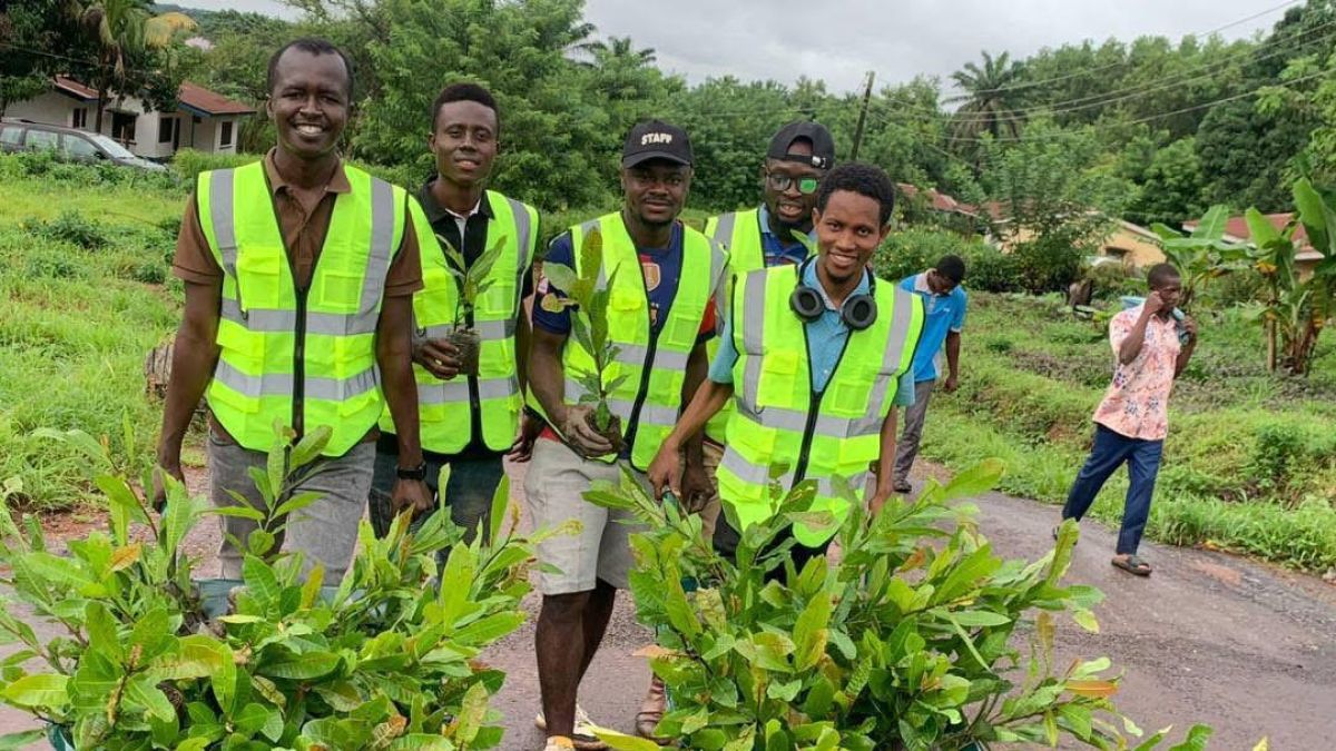 young men with green reflector vests and wheelbarrows full of plants