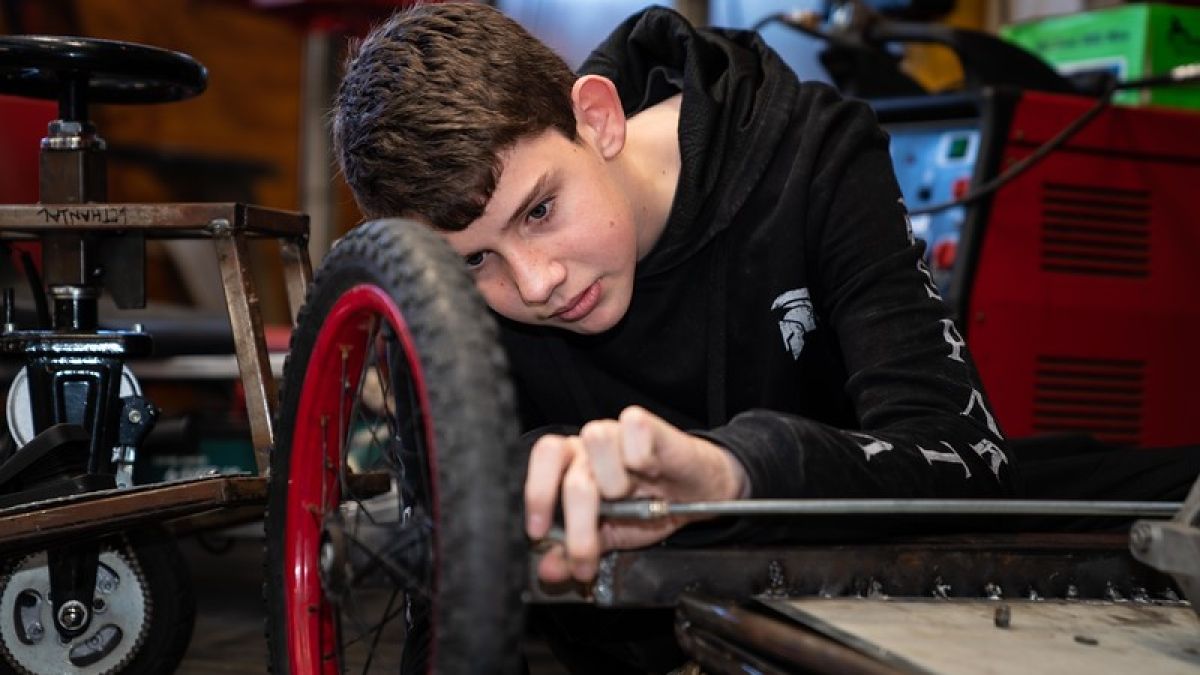 Boy working on axle of wheel