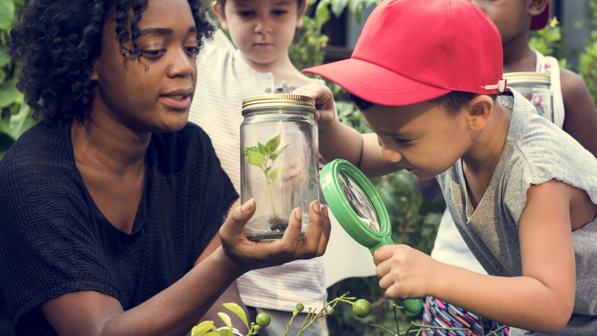 Young children examining plant with adult woman