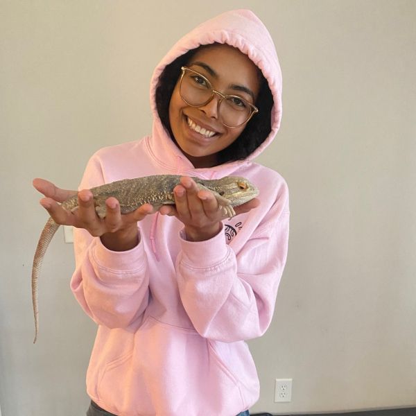 A person in a pink sweater holding a lizard