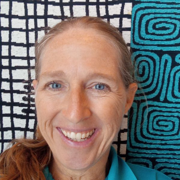 A Person In A Light Blue Collared Shirt Smiling At The Camera with a Black, White, and Blue Background