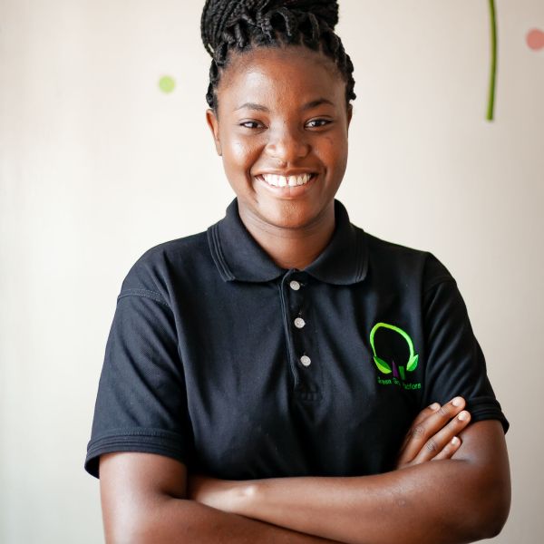 CEE Change Joy Hayley Munthali wearing a black polo with the Green Girls Platform logo smiling with her arms crossed