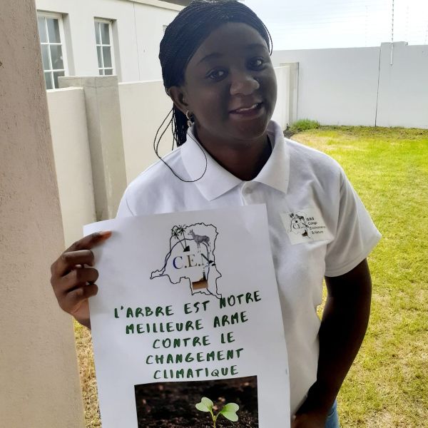 CEE Change Fellow Mariam Kabamba holding a sign in French that says, "The tree is the best weapon against climate change"