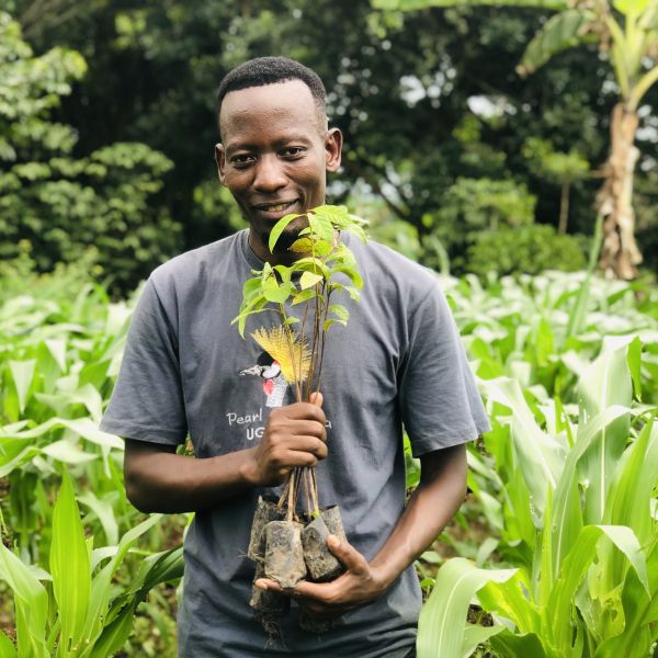 CEE Change Fellow Richard Tusabe holding plants in a green field
