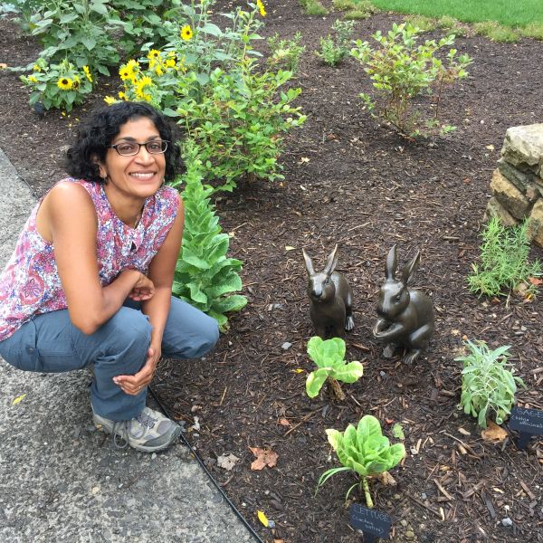 CEE Change Fellow Sarada Sangameswaran kneeling next to a garden with two rabbit statues