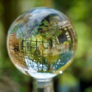 closeup of water drop reflecting metal fence and garden