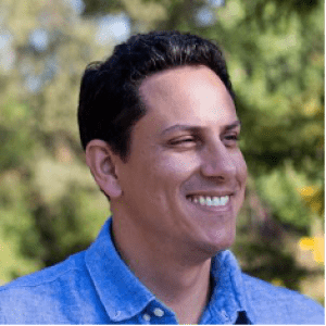 Jaime Gonzalez outdoors in a blue shirt, smiling and looking to the right