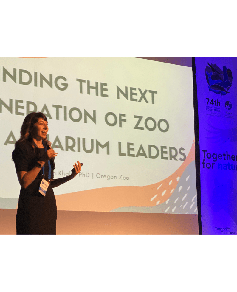 Kathayoon Khalil stands in front of a large screen, presenting on the next generation of zoo and aquarium leaders.