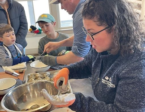 Group of people seated at a table, shucking oysters