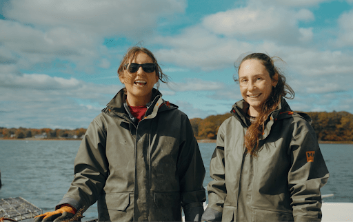 Two sisters pose for the camera while enjoying a sunny day outside near the ocean