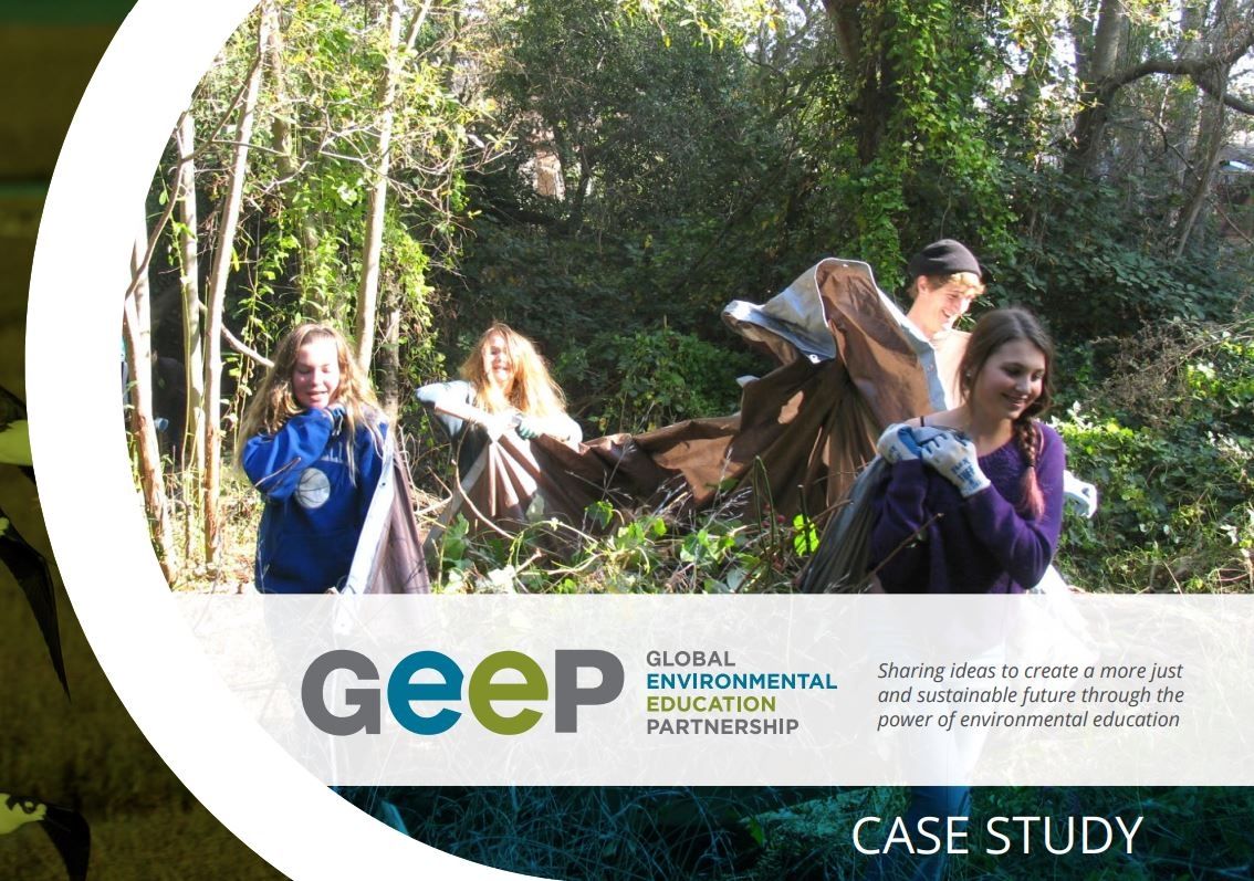 a group of students in forested habitat carrying branches and woody debris in a large tarp