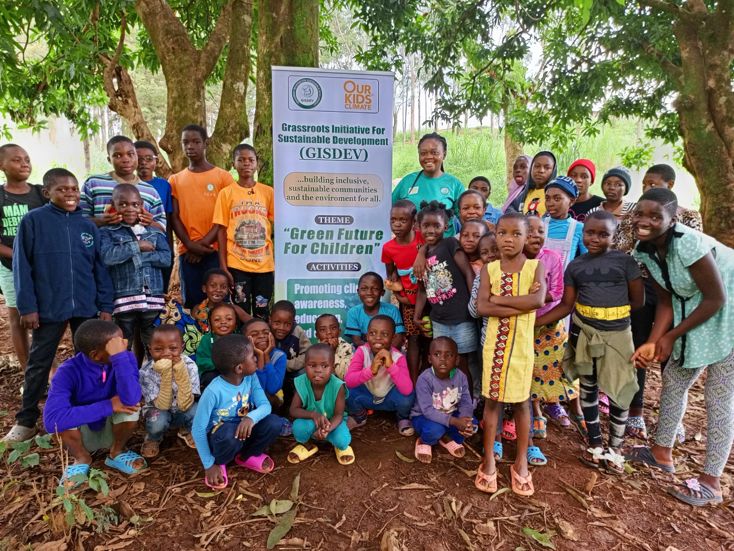 A group of young children posing next to a large sign that read's GisDev, "Green Children for the Future."