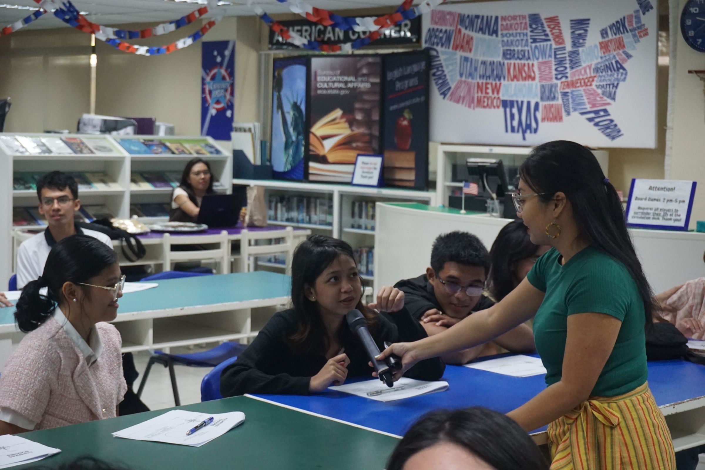 A woman holding a microphone up to a young girl, who is speaking.