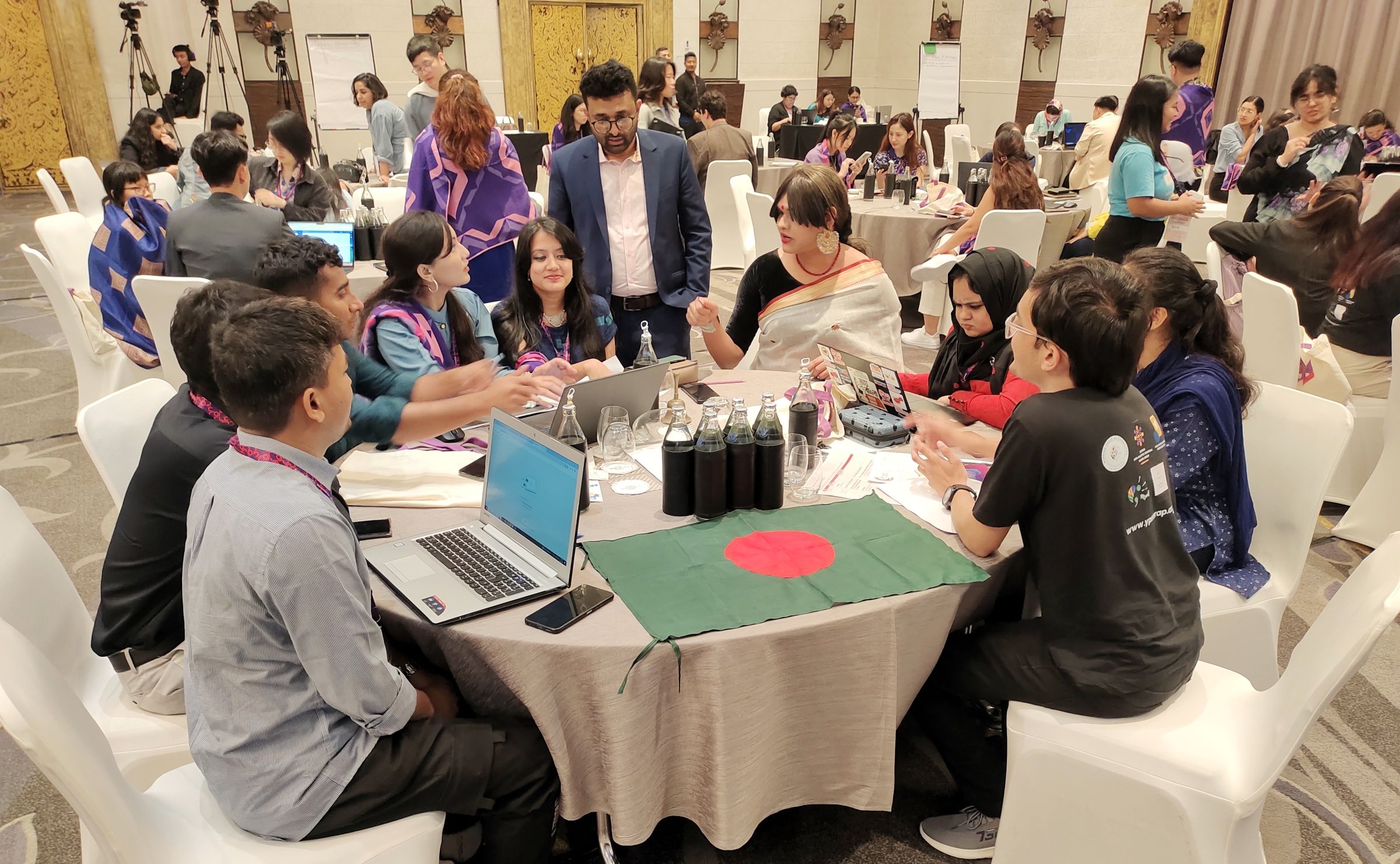 Several groups of people in conversation at round tables.