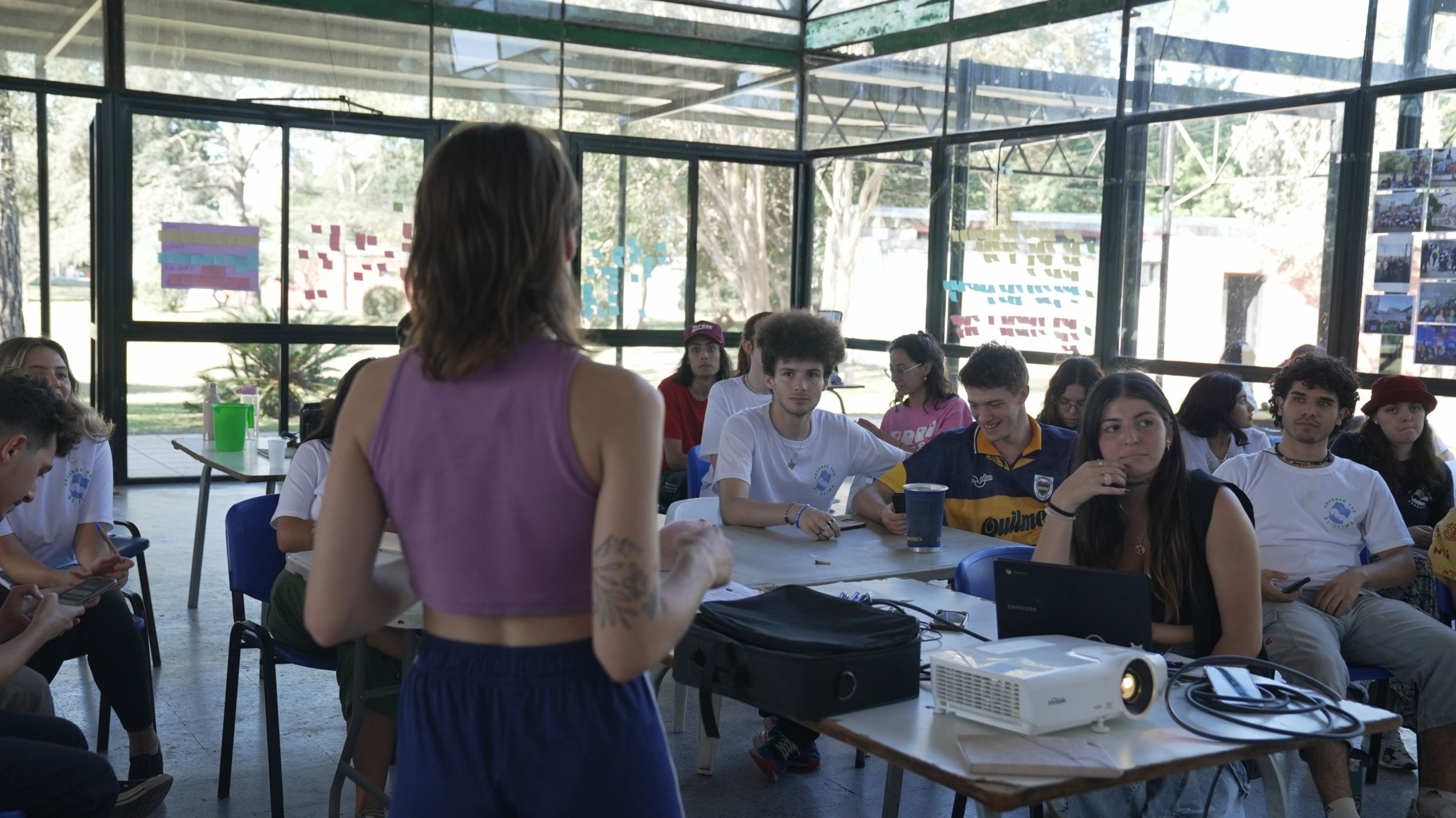 A woman speaking in front of a group of other young people.