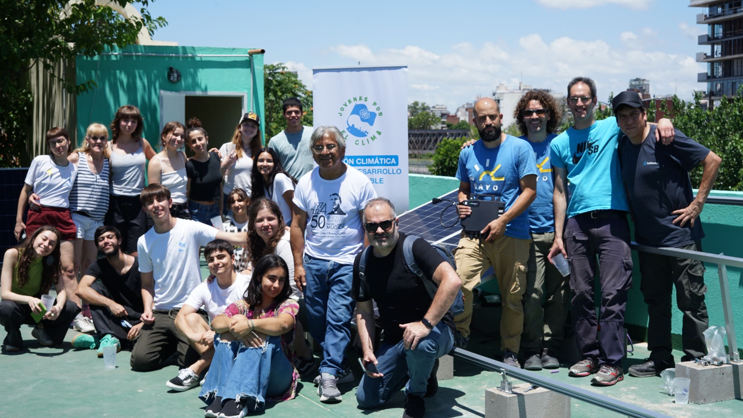 A large group of people posing near solar panels. 