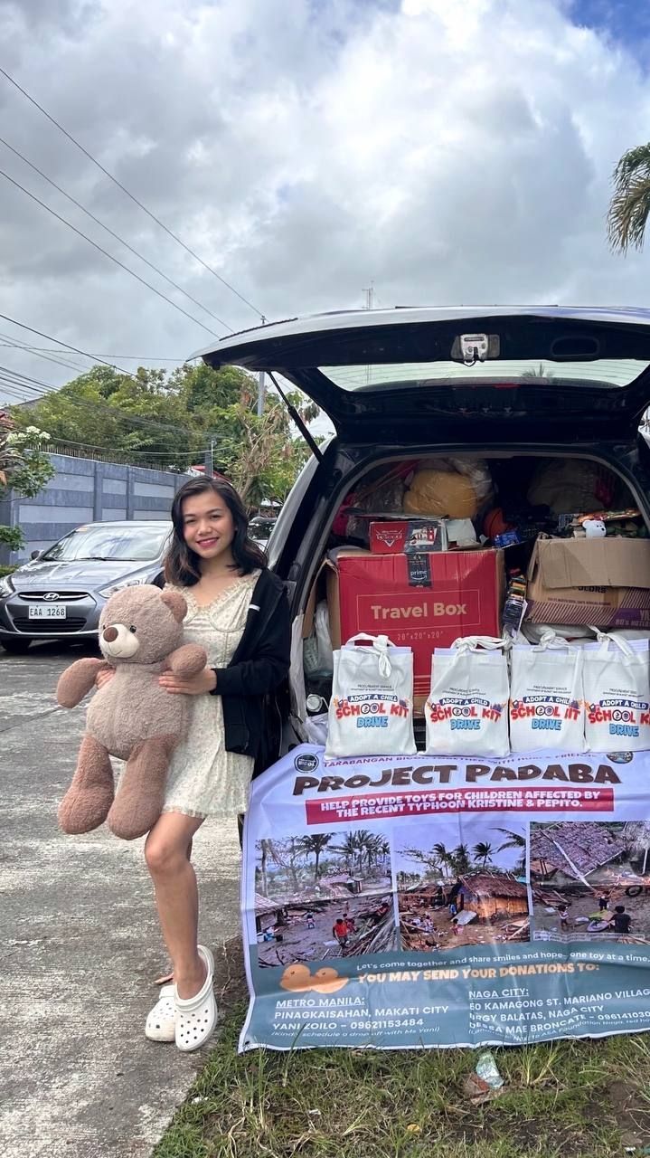 A woman posing next to a car trunk full of school kits.